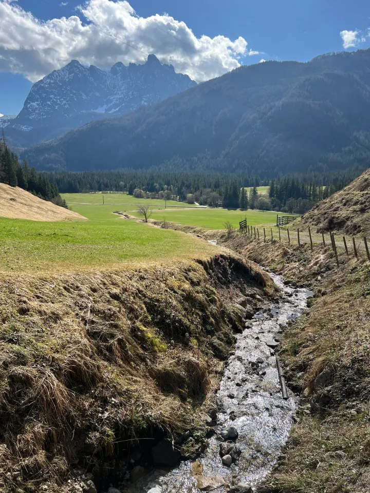 Almwiesenpfad mit Schneeresten und Blick zum Kaisergebirge